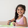 Little girl smiling while she cut a paper with cissor