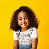 Little girl smiling in front of a yellow background
