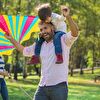 Son sitting on father's neck and flying a kite