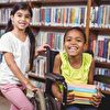Wheelchair girl smiling with her friend in the library