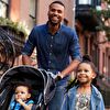 Father pushing baby carriage and her daughter walking next to him