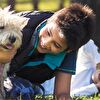 Boy playing with white dog on the ground - landscape cut