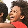 Girl riding on her mother's back and laughing