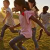 Kids Running Freely Through Green Field