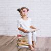 Little Girl in White With Pink Eyeglasses Sitting on Books
