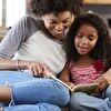 Mother and Daughter Reading Book Together on the Couch